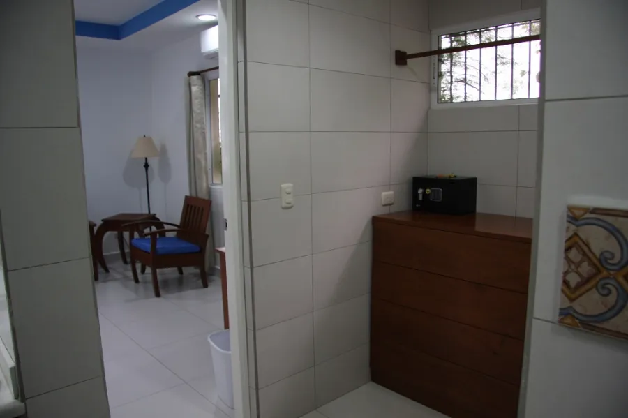 A room entrance with a wooden dresser, wall safe and a reading chair